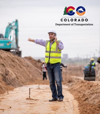civil engineer on the phone and pointing at construction equipment at construction site